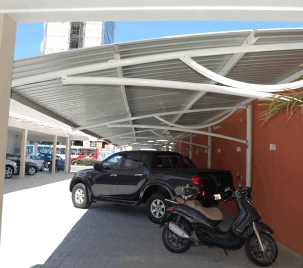 Cobertura de telha branca sobre caminhonete e moto em garagem